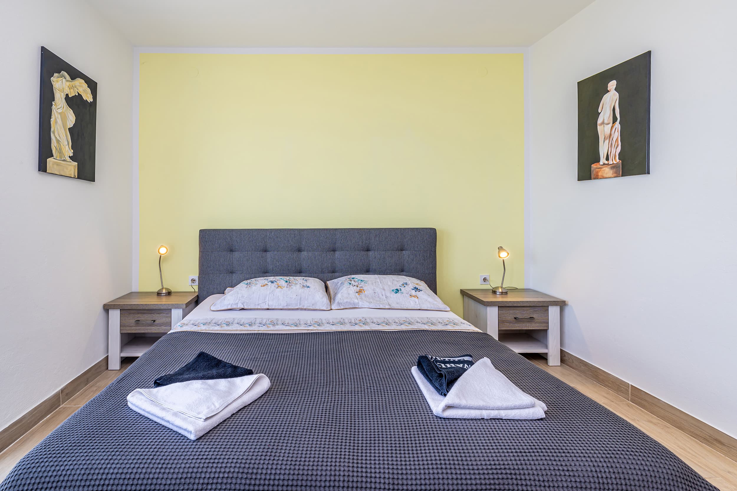Queen bedroom with an upholstered headboard, bedside lamps and fresh towels laid out on the bed