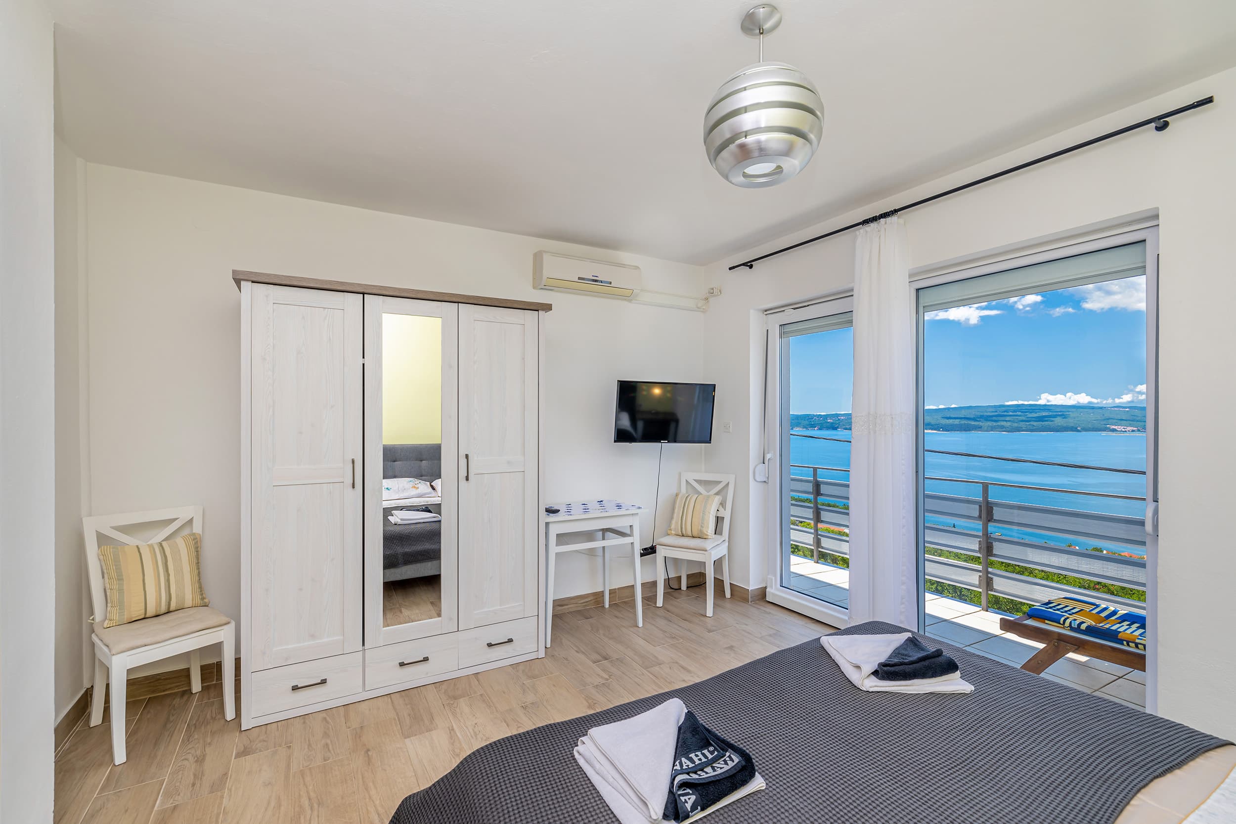 Family bedroom with a wardrobe, extra seating and a balcony door opening onto the Adriatic