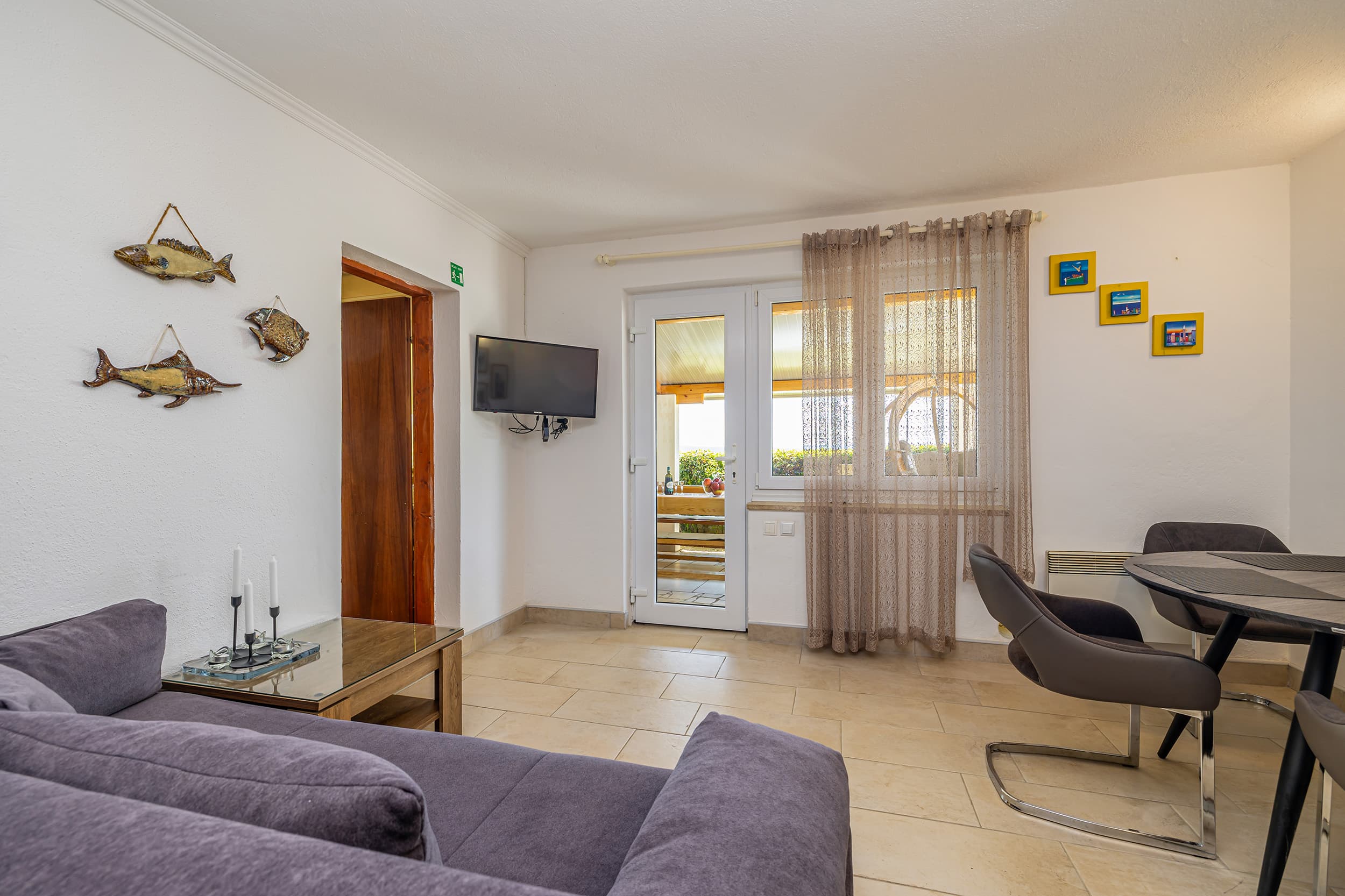Living area with a sofa, flat-screen TV and dining table beside the door to the terrace
